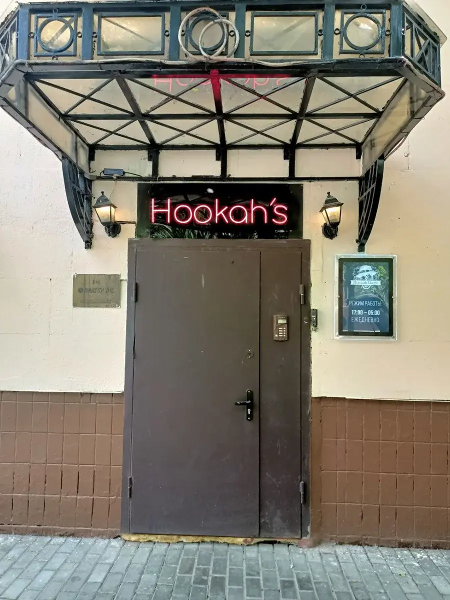Уличная неоновая вывеска Hookah's на входе — красный неон на тёмном фасаде